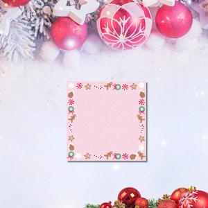 May include: A festive Christmas-themed image featuring red ornaments, white star-shaped decorations, and a pink notepad with a gingerbread border. The background includes snow-covered branches and a white surface, creating a holiday atmosphere.