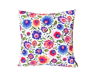 May include: A white pillow with a floral pattern in shades of pink, red, blue, and green. The flowers are stylized and have a folk art feel.