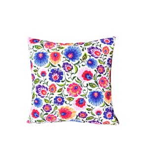 May include: A white pillow with a floral pattern in shades of pink, red, blue, and green. The flowers are stylized and have a folk art feel.