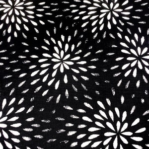 May include: Black and white fabric with a repeating pattern of white stylised flowers. The flowers are made up of small white petals radiating outwards from a central point.