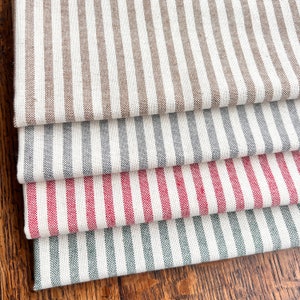 May include: Four different striped fabric swatches, stacked on top of each other. The top swatch is brown and white, the second is grey and white, the third is red and white, and the bottom is green and white.