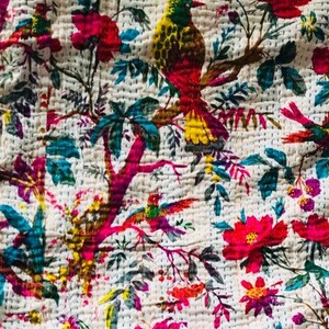 May include: A white kantha quilt with a floral and bird pattern. The quilt features pink, yellow, green, and blue colors. The quilt is made of cotton and is hand-stitched.