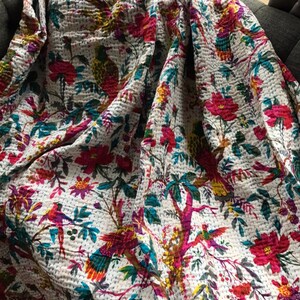 May include: White cotton quilt with a floral and bird print. The quilt features a variety of colors, including pink, red, blue, green, and yellow. The birds are depicted in a variety of poses, including flying, perched, and singing.