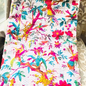 May include: A white kantha quilt with a floral and bird pattern. The quilt features bright pink, yellow, green, and blue colors. The quilt is made of cotton and is hand-stitched.