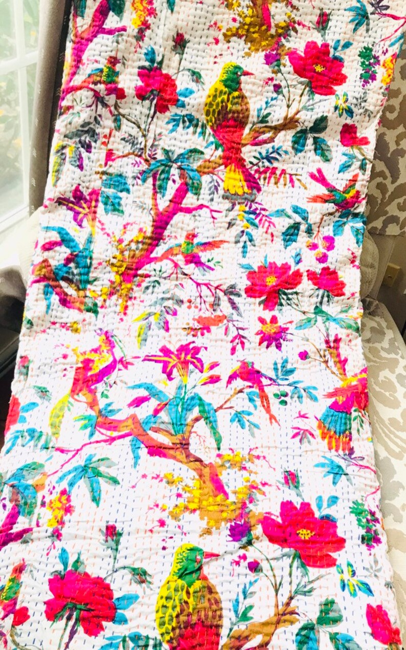 May include: A white kantha quilt with a floral and bird pattern. The quilt features bright pink, yellow, green, and blue colors. The quilt is made of cotton and is hand-stitched.