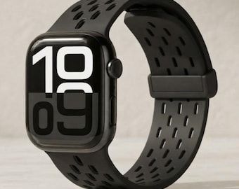 May include: A black smartwatch with a rectangular screen displaying the time 10:09 in large white and grey numerals. The watch features a flexible black silicone band with a perforated pattern of small oval cutouts and a matching black loop.