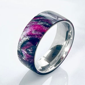 May include: A silver band ring with a pink and black marbled epoxy inlay.