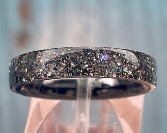 May include: A black ring with iridescent glitter embedded in the surface.