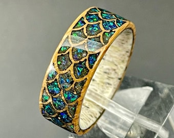 May include: A wooden ring with a blue and green iridescent inlay in a scale pattern.