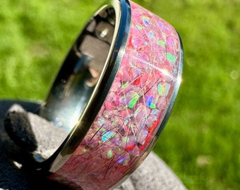 May include: A silver ring with a pink and iridescent inlay. The inlay is made of small pieces of opal and other gemstones.