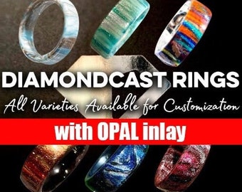 May include: A collection of Diamondcast rings with opal inlay, showcasing various colors and patterns. The rings feature a range of hues, including blue, green, orange, and red, with a glossy finish. The text "DIAMONDCAST RINGS" and "with OPAL inlay" are visible.