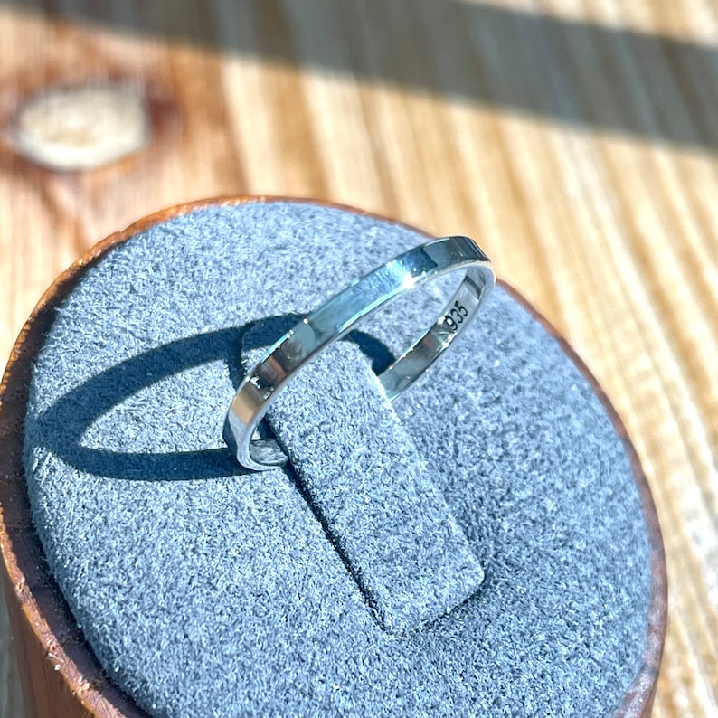 Op de afbeelding: Een zilveren ring met een gladde, gepolijste afwerking. De binnenkant van de band is gestempeld met het nummer "925".