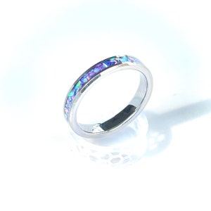 May include: A silver band ring with a thin band of iridescent purple and blue opal inlay.