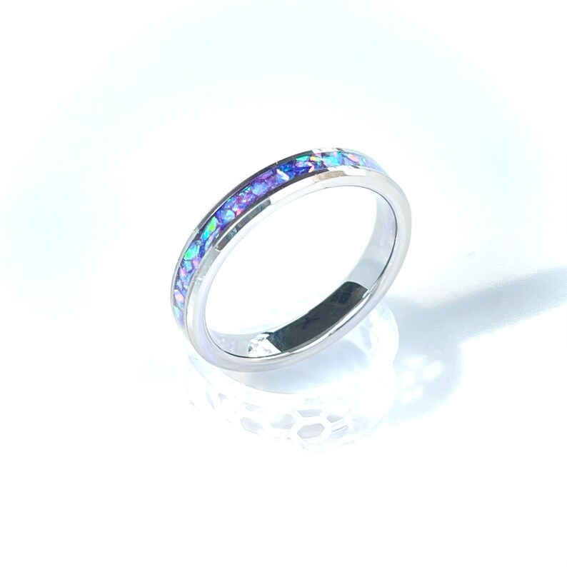 May include: A silver band ring with a thin band of iridescent purple and blue opal inlay.