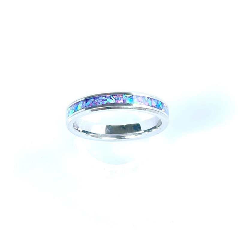 May include: A silver band ring with a thin line of iridescent purple and blue opal inlay.