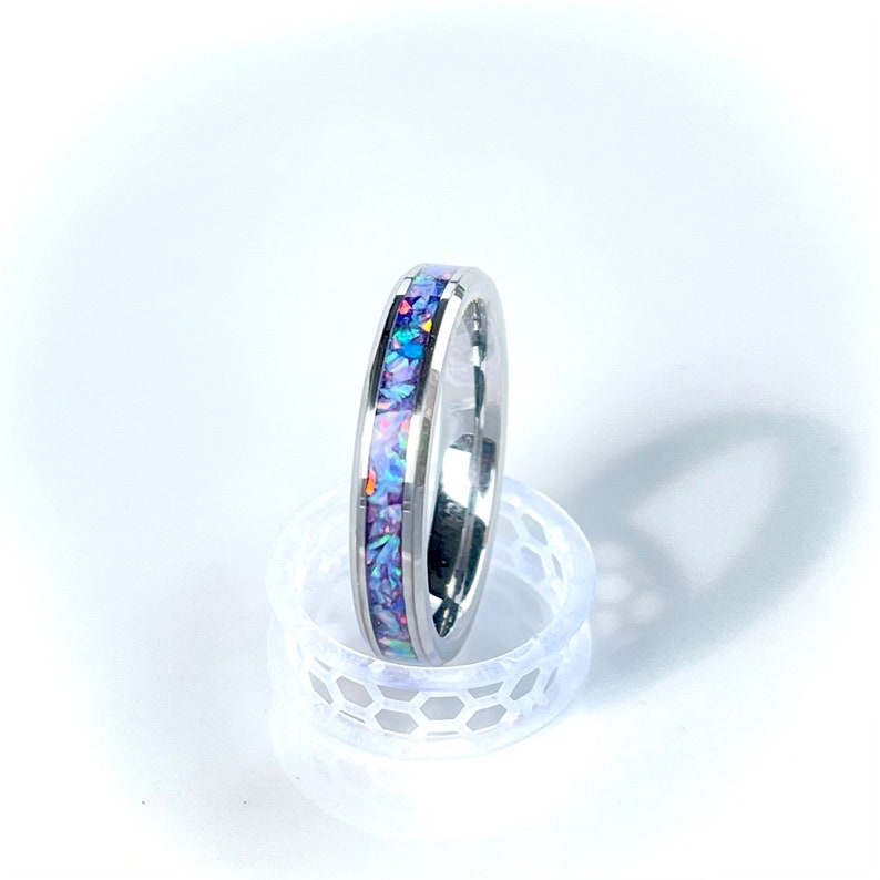 May include: A silver band ring with a thin purple opal inlay.