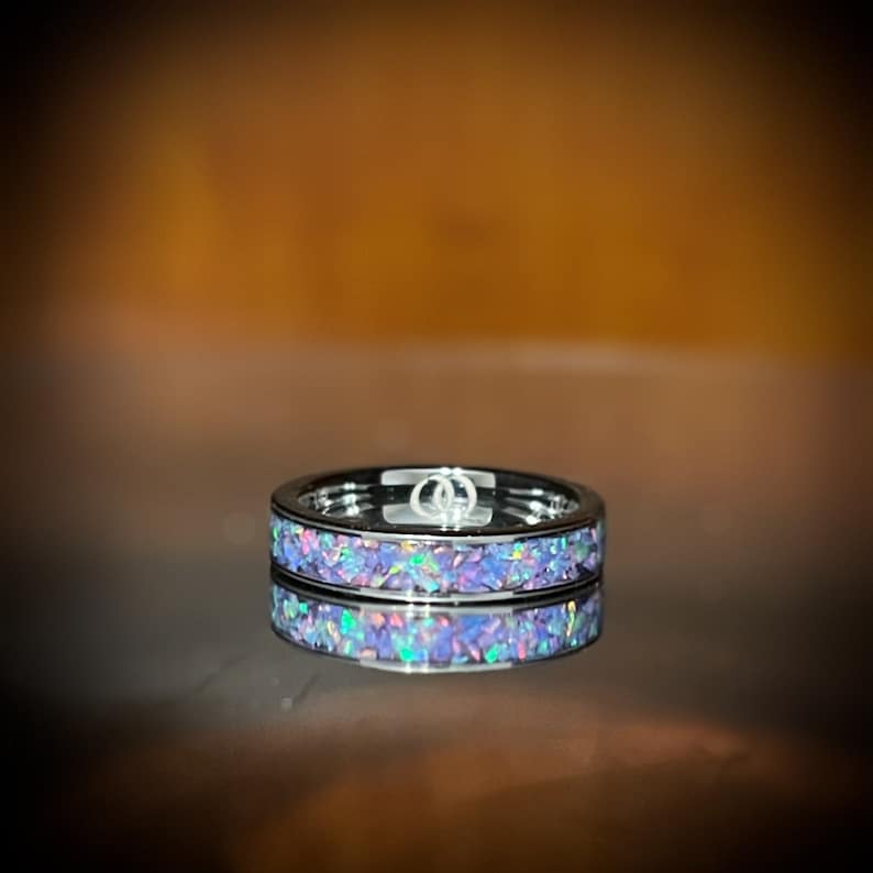 May include: A silver band ring with a thin band of iridescent purple opal inlay.
