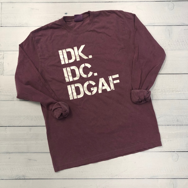 May include: A maroon long-sleeve t-shirt with the text "IDK. IDC. IDGAF" printed in white on the front.
