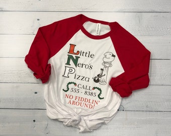 Puede incluir: Camiseta de estilo béisbol blanca y roja con un gráfico de una pizzería llamada "Little Nero's Pizza" con el número de teléfono 555-8385 y el texto "No fiddlin' around!"