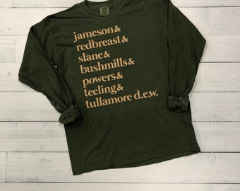 Op de afbeelding: Een donkergroen longsleeve t-shirt met de namen van verschillende Ierse whisky's bedrukt in een lichtbruine kleur. De tekst luidt: "jameson & redbreast & slane & bushmills & powers & teeling & tullamore d.e.w."