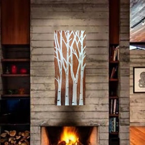 May include: A rectangular wooden artwork featuring a design of white birch trees against a brown background. The artwork is mounted on a gray stone fireplace, with a fire burning in the hearth below. The room has a modern, rustic aesthetic.