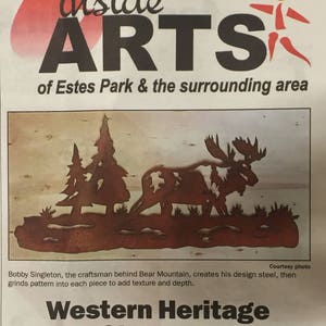 May include: A black and white newspaper clipping with the headline "Western Heritage Design Show scheduled this weekend". The article is about a local craftsman who creates metal sculptures. The image shows a metal sculpture of a moose and trees.