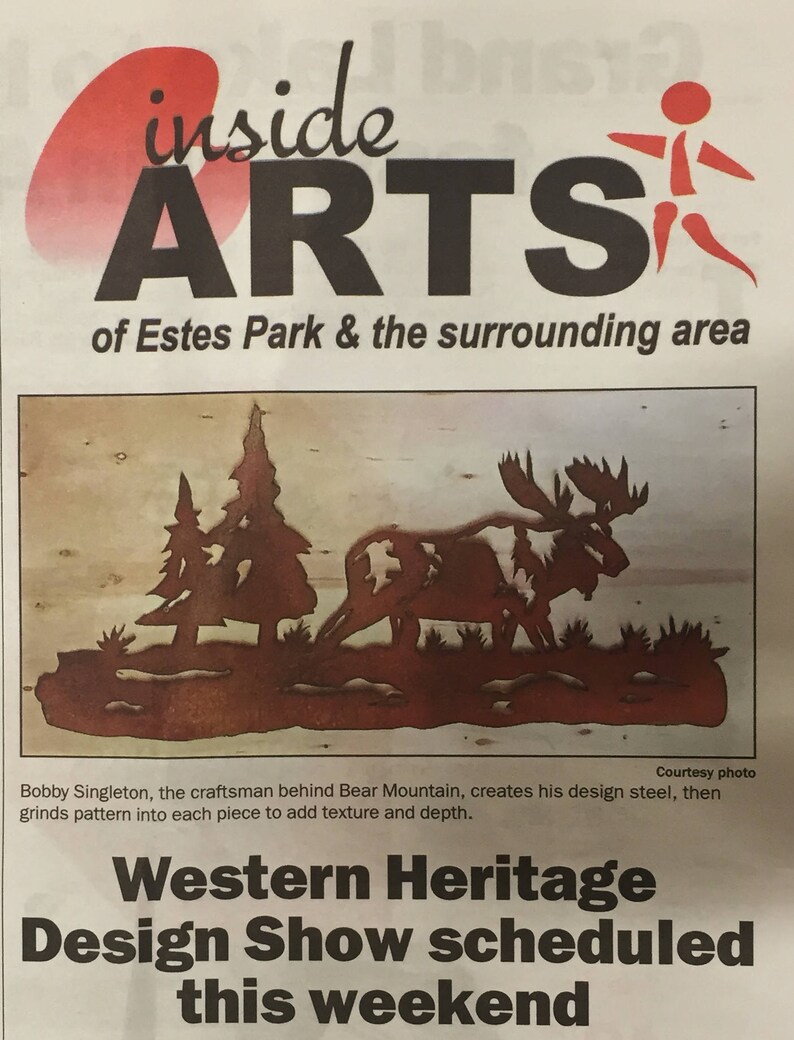 May include: A black and white newspaper clipping with the headline "Western Heritage Design Show scheduled this weekend". The article is about a local craftsman who creates metal sculptures. The image shows a metal sculpture of a moose and trees.