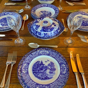 May include: A table setting featuring blue and white patterned china plates, bowls, and a serving dish. The table is laid with cutlery and wine glasses.