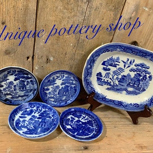 May include: A set of five blue and white porcelain plates featuring a willow pattern design. The set includes a large oval serving platter and four smaller round plates.