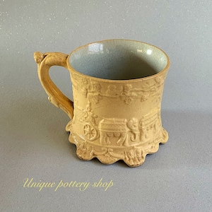 Puede incluir: Una taza de cerámica amarilla con un diseño detallado de un carruaje tirado por caballos. La taza tiene un borde festoneado y un asa.