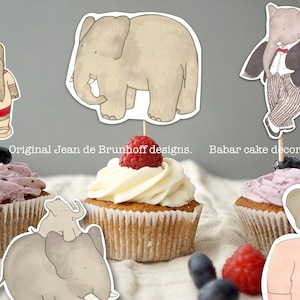 May include: Three cupcakes decorated with various elephant-themed toppers. The cupcakes are topped with purple, white, and pink frosting. The toppers feature a cartoon elephant wearing a red and white striped shirt, a cartoon elephant wearing a black suit, and a cartoon elephant wearing a pink shirt. The text "Original Jean de Brunhoff designs. Babar cake decorations" is visible on the image.