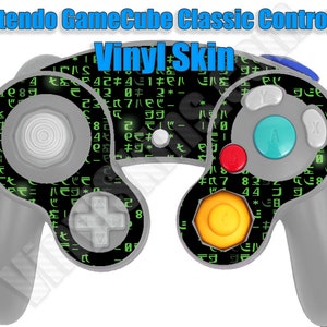May include: A gray Nintendo GameCube Classic Controller with a vinyl skin. The skin features a black background with green characters and symbols. The controller has a blue, red, and yellow button. The text "Nintendo GameCube Classic Controller" and "Vinyl Skin" are visible.
