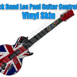 May include: A black Les Paul guitar controller with a Union Jack design vinyl skin. The guitar has a red, white, and blue Union Jack design with a distressed look. The guitar has a black neck with colored buttons.