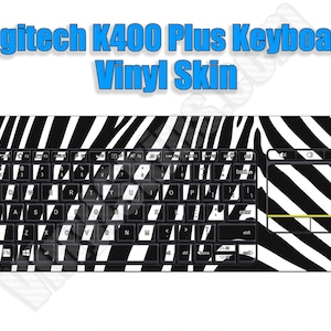 May include: A black and white zebra print vinyl keyboard skin for a Logitech K400 Plus keyboard. The skin covers the entire keyboard, including the keys, the touchpad, and the function keys.