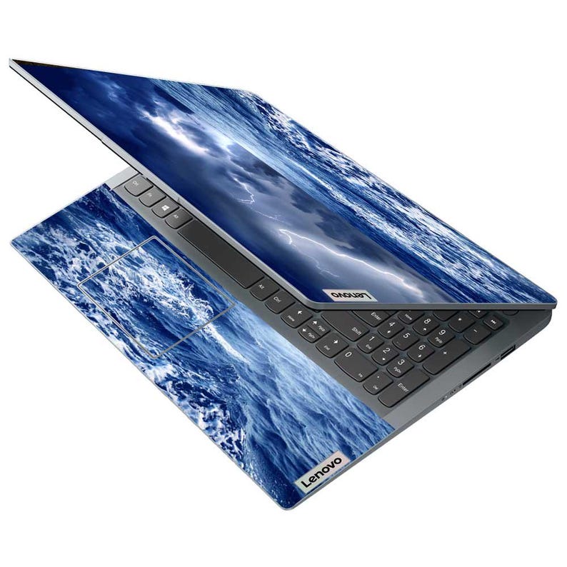 May include: A Lenovo laptop with a dark gray keyboard and a blue ocean wave design on the lid and palm rest. The screen displays a stormy ocean scene with lightning. The Lenovo logo is visible.