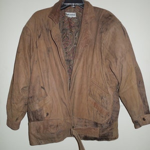 May include: A brown leather jacket with a paisley lining and a belt. The jacket has a zipper closure and two pockets. The jacket is worn and has a distressed look.