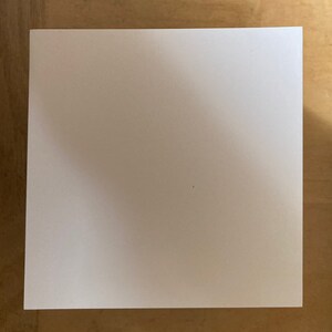 May include: A plain white square piece of paper.