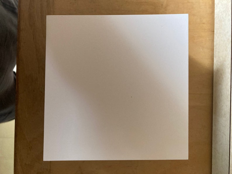 May include: A blank white sheet of paper on a wooden surface.