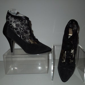 May include: A pair of black high-heeled shoes with lace detailing. The shoes have a pointed toe and a stiletto heel.
