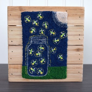 May include: A blue and green needlepoint design of a glass jar filled with glowing fireflies against a dark blue background with a white moon.