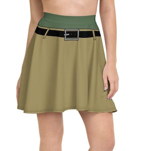 Puede incluir: Una falda skater de color caqui con un cinturón negro y una cintura verde. La falda está hecha de una tela suave y cómoda y tiene un ajuste favorecedor.