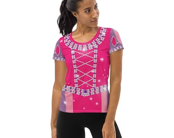 May include: A pink t-shirt featuring a design resembling a princess dress. The shirt has a jewel-encrusted neckline and bodice, with a criss-cross pattern. The sleeves and sides are accented with purple and pink details. The shirt is worn by a person.