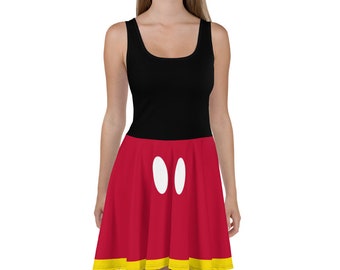 May include: A red and black dress with a white circle design. The dress has a black bodice and a red skirt with a yellow trim. The skirt has two white circles on the front.