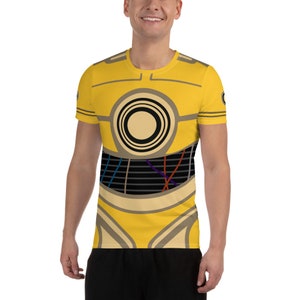 May include: A yellow short-sleeved shirt with a graphic print of a robot. The robot has a large circular eye and a grid pattern on its chest.