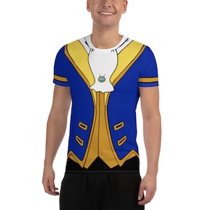 May include: A blue and gold short-sleeved t-shirt with a print of a prince's costume. The shirt features a blue jacket with gold trim, a white cravat, and a gold button with a blue gem.