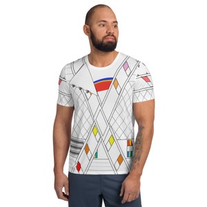May include: White short-sleeved t-shirt with a geometric pattern in black, red, yellow, blue, and orange. The pattern features intersecting lines and squares.