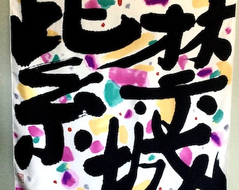 May include: A square white scarf featuring large, bold black brushstroke calligraphy characters. The background is decorated with scattered, abstract watercolor-style paint splatters in vibrant shades of pink, teal, yellow, and purple.