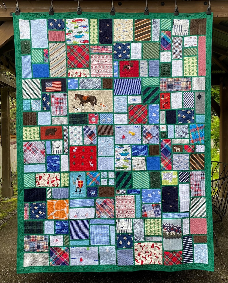 May include: A patchwork quilt featuring a green border and numerous rectangular fabric blocks in various patterns, including plaid, stripes, stars, and animal prints. Several blocks display embroidered motifs like a horse, a knight, and the letters JR.