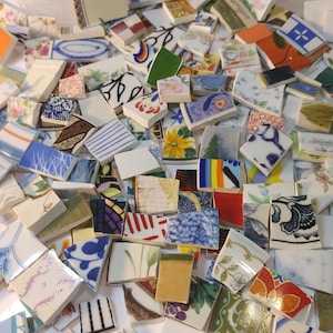May include: A collection of broken ceramic tiles with various floral and geometric patterns. The tiles are in shades of blue, white, yellow, and red. Some tiles have visible text. The image is taken from a close-up perspective.