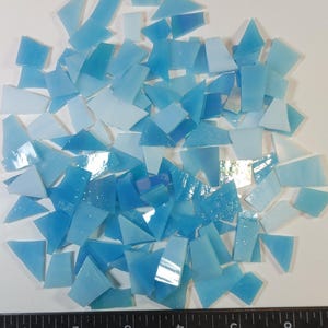 May include: A collection of small, irregularly shaped, light blue glass mosaic tiles. The tiles are scattered across a white surface, with a ruler along the bottom edge. The text "debscolorfulcorner" is in the bottom right corner.